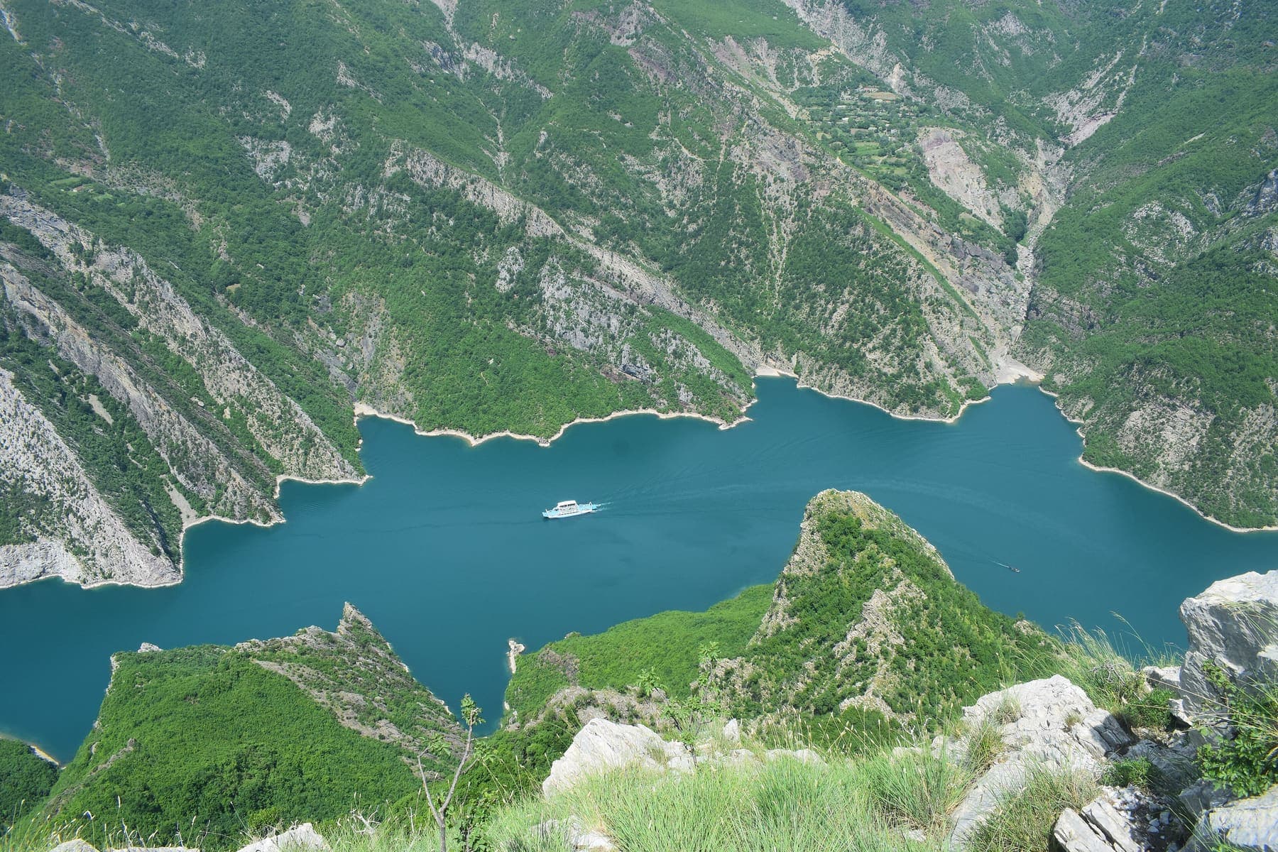 Ferry on Komani Lake between steep gorge walls